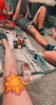 three people sitting on the floor with their feet covered in tattoos and nail polishes