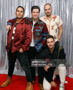 three men posing for the camera in front of a silver backdrop with tinsel foil