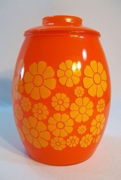 an orange vase with yellow flowers painted on the outside and inside, sitting on a white surface