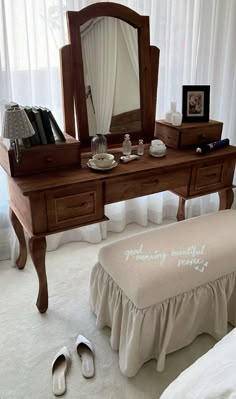 a dressing table with a mirror, stool and slippers on the floor next to it