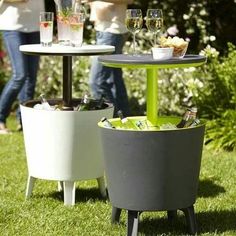 an outdoor table with two wine glasses and food on it in the middle of some grass