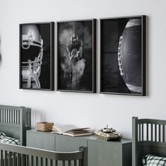 three black and white photographs hang on the wall above a crib with two footballs