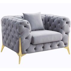 a gray velvet chair with gold legs and buttons on it's armrests