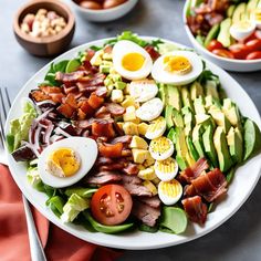 a salad with hard boiled eggs, bacon and avocado on it is shown