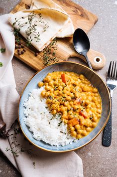 a plate with rice, beans and carrots on it next to a wooden cutting board