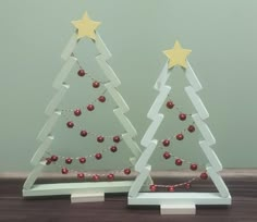 two small wooden christmas trees with gold stars on top and red baubons hanging from them