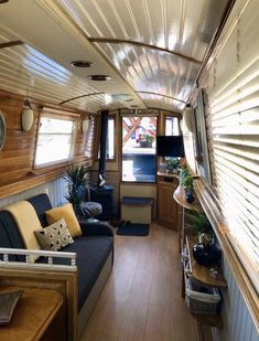 the inside of a houseboat with wood flooring and walls, windows, and couches