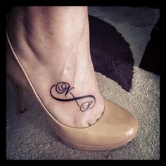 a woman's foot with a small tattoo on the ankle that has a ribbon in it