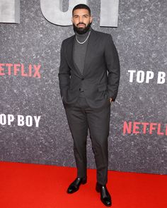 a man in a suit standing on a red carpet