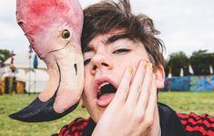 a young man holding his face next to a fake flamingo