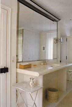 a kitchen with a marble counter top next to a white sink and large mirror on the wall