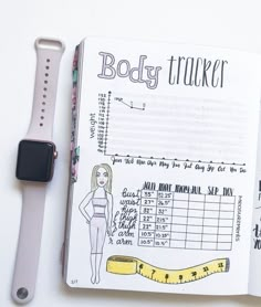 an apple watch and a notebook with the body tracker on it next to a pen