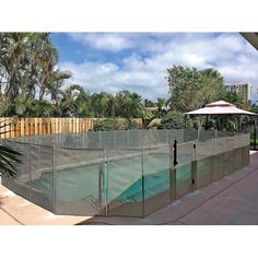 a fenced in tennis court next to a palm tree