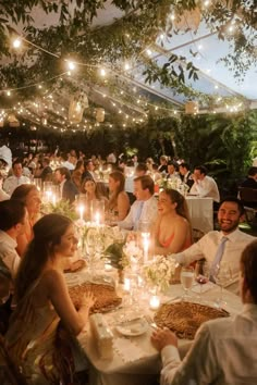 a group of people sitting around a table with food and candles in front of them