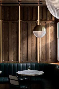 a table and chairs in a room with wooden paneling on the wall behind it