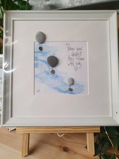 a white frame with some rocks on it and a quote written in the middle that says, follow your dreams