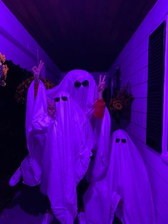 two people dressed in white ghost costumes holding up their hands