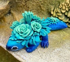 a blue lizard with flowers on it's back sitting on a rock next to another animal