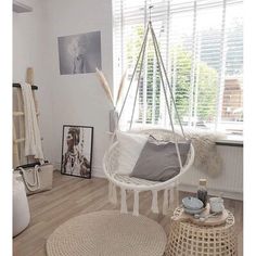 a white hammock hanging from the ceiling in a room with wood flooring