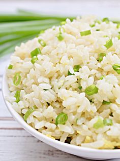 a white bowl filled with rice and green onions