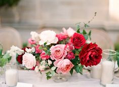 an arrangement of flowers on a table with candles and napkins in front of them