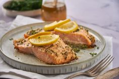 two salmon fillets on a plate with lemon wedges