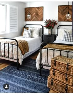 two twin beds in a bedroom with blue rugs and wooden wall art above them