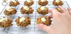 a hand is reaching for some cookies on a cooling rack with icing and butter