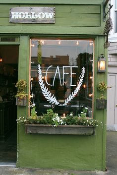 the front window of a cafe with plants in it