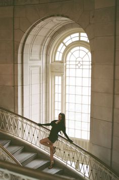 a woman standing on top of a metal handrail in front of a large window