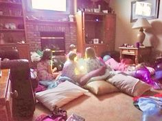 a group of people sitting in a living room next to a fire place with gifts on the floor