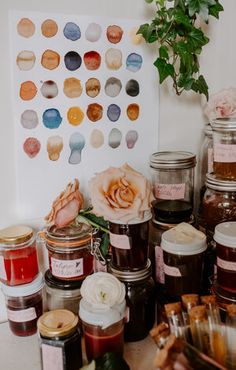 jars filled with honey sit on a table next to a potted plant and flowers