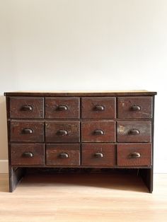 an old wooden dresser sitting on top of a hard wood floor next to a white wall