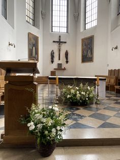 the interior of a church with pews and flowers in vases on the floor