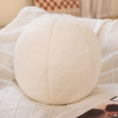 a large white ball sitting on top of a bed next to a magazine and lamp