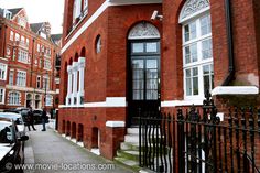 a red brick building with white trim on the front and side windows, next to a black iron fence