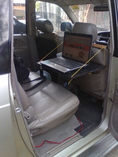 the interior of a vehicle with a laptop on the back seat and an open door