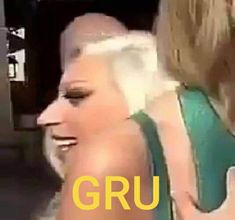 two women are talking to each other in front of a camera with the caption gru