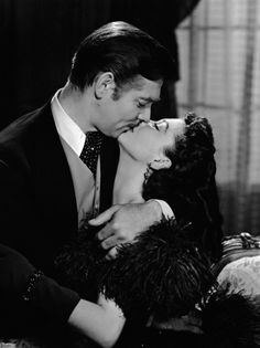 a man kissing a woman on the cheek in a black and white photo by photographer robert tonkin