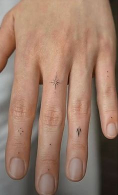 a person's hand with a small star tattoo on the middle finger and an arrow in the middle