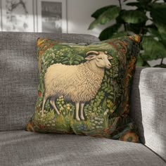 a pillow with a sheep on it sitting on a couch next to a potted plant