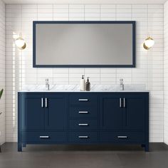 a bathroom vanity with two sinks and a large mirror above it, against a white brick wall