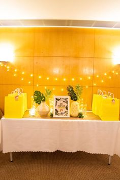 the table is set up with yellow bags and pineapples on it for guests to eat