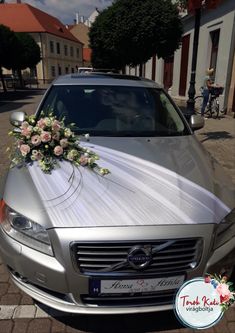 a silver car parked on the side of a road with a bouquet of flowers attached to it