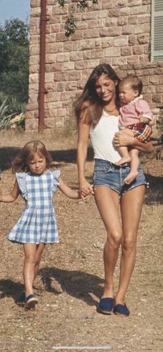 two women and a baby walking in front of a brick building