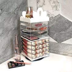 an assortment of cosmetics and makeup products are stacked on a counter in front of a marble wall