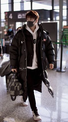 a man wearing a face mask walking through an airport