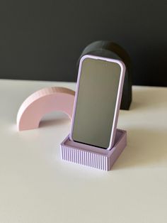 an electronic device sitting on top of a white table next to a black and pink object