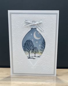 an ornament shaped card with trees and moon on it