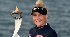 a woman is holding up a trophy in front of the water with birds on it